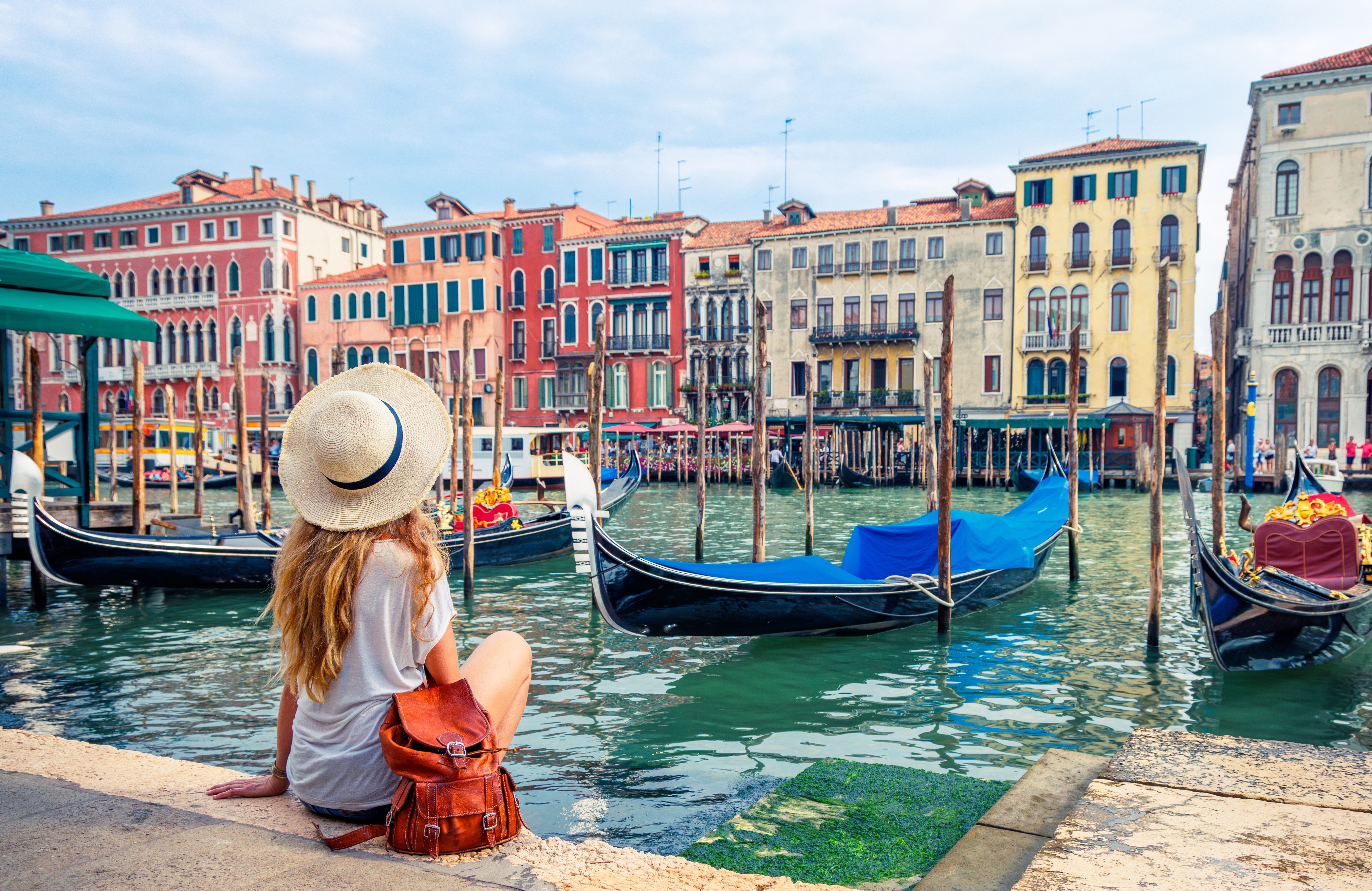 Women looking at buildings across a Venice canal.