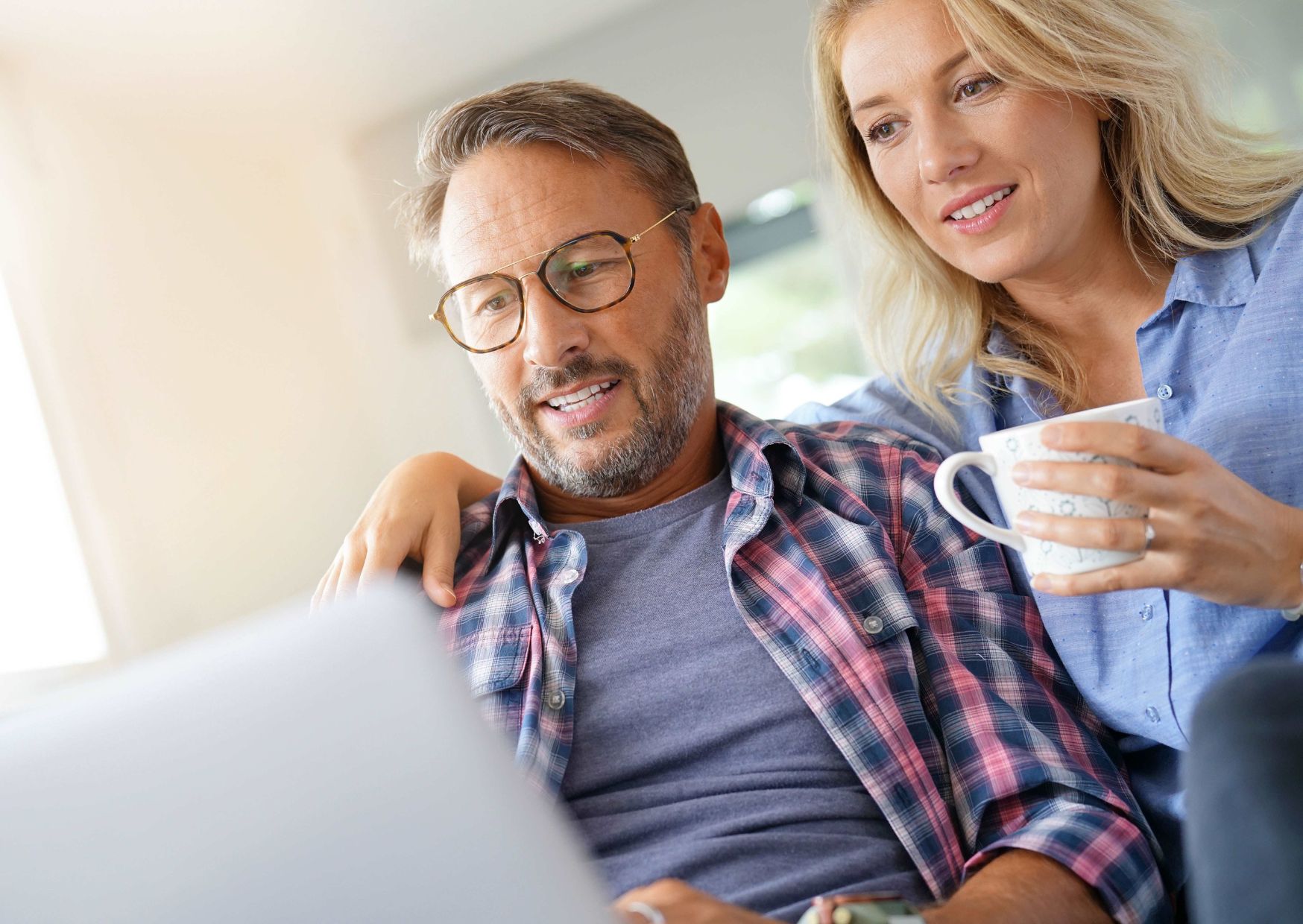 Couple planning holiday budget at a laptop.